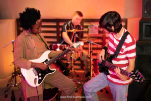 A group of musicians playing various instruments together in a lively room setting