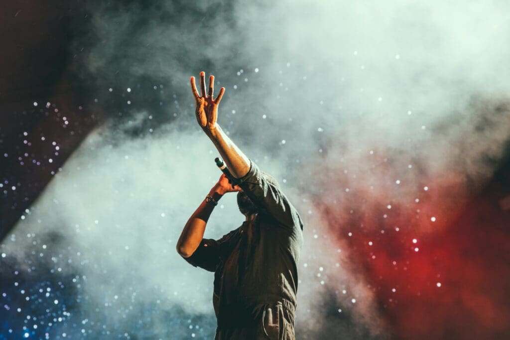 man on stage with his hand in the air performing live music